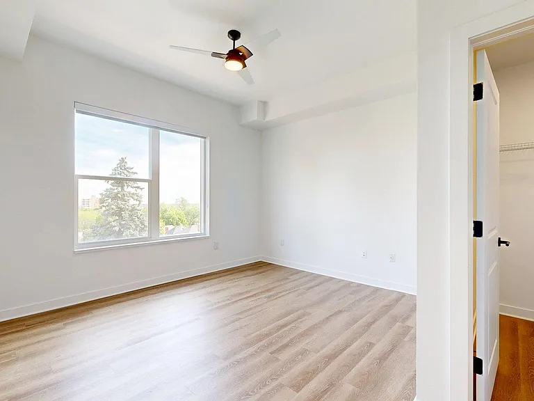Spacious apartment bedroom with large closet and wood style floors.