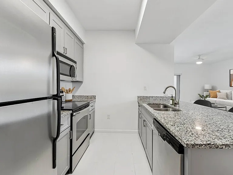 Renovated Package I kitchen with stainless steel appliances, tile backsplash, granite countertops (in most homes), and grey cabinetry