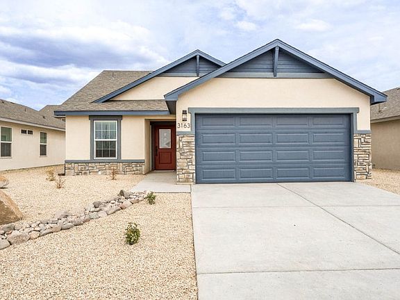 Single-story house with a blue garage door and trim, stone accents, red front door, and beige exteri