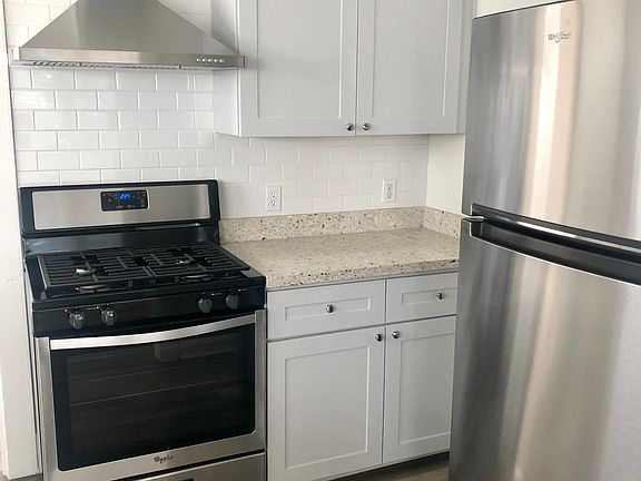 Kitchen with granite countertops, stainless-steel appliances and range hood