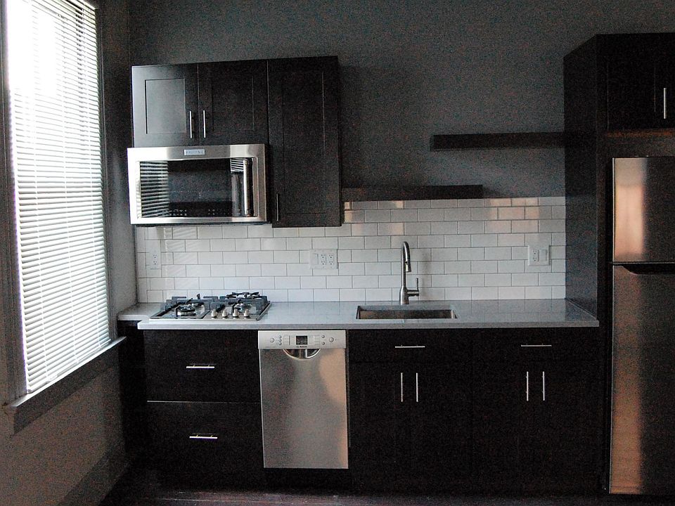 stainless kitchen with stone countertop and subway tiled backsplash