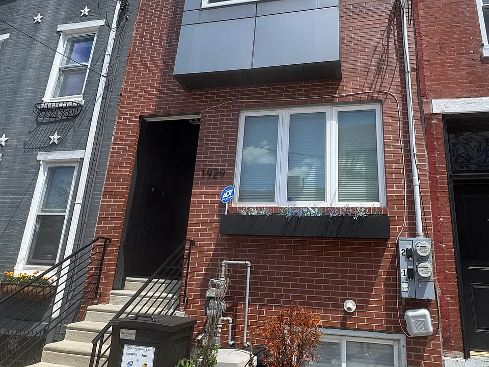 View from the front, picturesque window, planters and a security box for packages.
