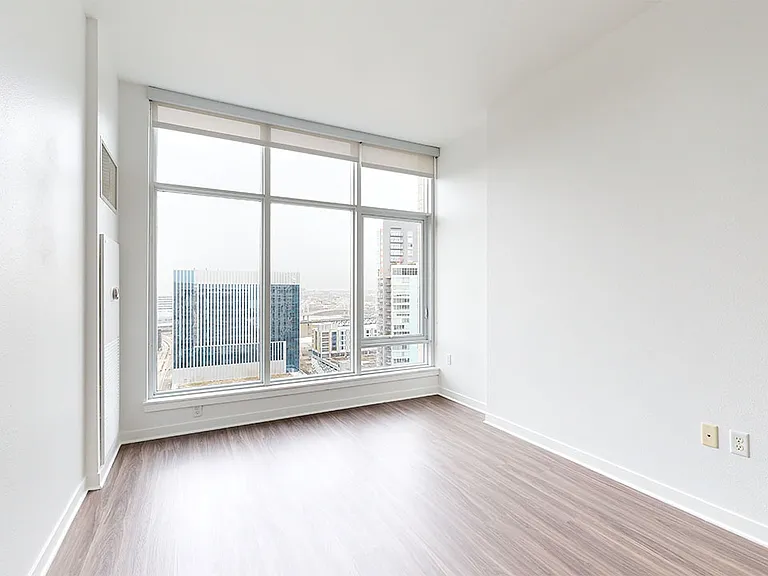 Spacious apartment bedroom with large closet, attached bathroom and wood style flooring.