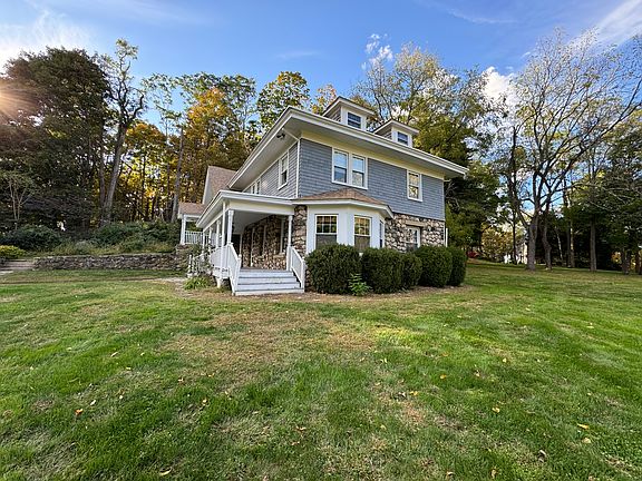Side exterior of stone & wood farmhouse with front porch.