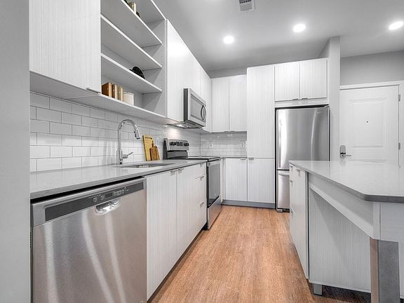 Kitchen with quartz stone countertops and white cabinetry with tile backsplash on hard surface flooring