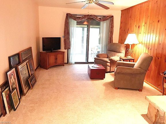 The back end of the living room leading to the enclosed back porch is carpeted in a neutral shade. The west facing wall is a qua