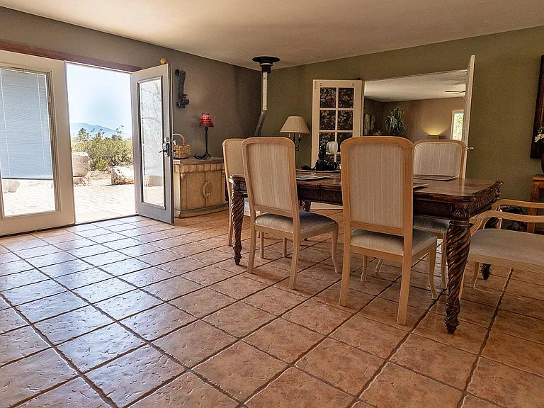 View of the dining table, front door is open, pellet stove in the corner and the master bedroom entrance is thru the open double doors on the right