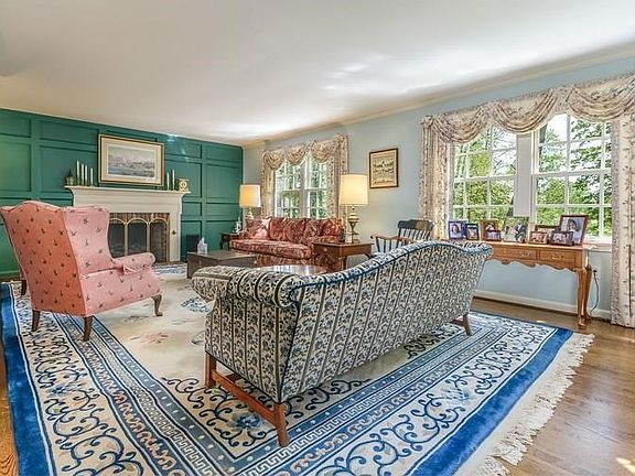 Welcoming living room with wood floors, fireplace and double windows for streaming morning light.