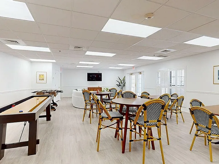 Inviting recreational room with modern lighting, stylish seating arrangements, and a sleek shuffleboard table.