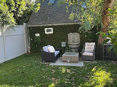 Backyard seating area with gas firepit table and chairs under large eucalyptus tree