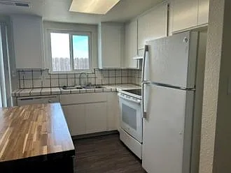 Kitchen with island work station, dishwasher, dual stainless steel sink, glass top stove, and refrigerator