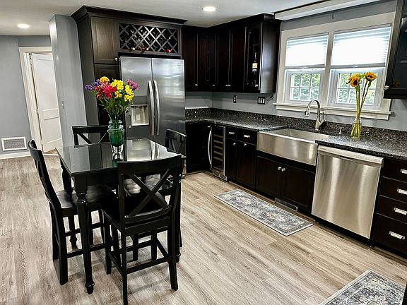 Modern kitchen with granite countertops, new flooring and appliances including refridgerator, stove, dishwasher, microwave and wine cooler.