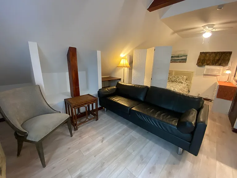 The studio has a comfy black leather sofa, guest chair, tables.