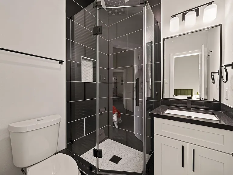 Stylish bathroom with a glass-enclosed walk-in shower, oversized tile surround, and a vanity with ample counter space.