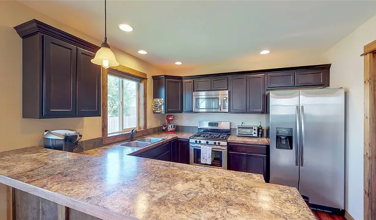 Fully stocked kitchen with stainless steel appliances and a large bar top dining area.