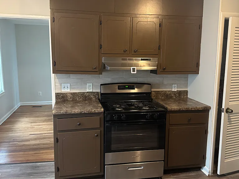 Stainless steel gas stove/hood and entrance to living room. Tankless gas water heater located in closet next to stove