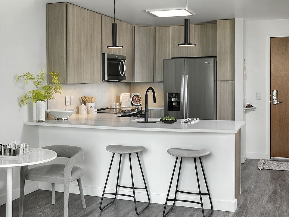 Apartment Kitchen with Stainless Steel Appliances, quartz counters and wood-like floors.