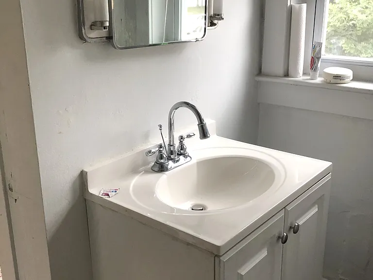Bathroom with vintage medicine cabinets, shower/tub combo and vanity with storage space.