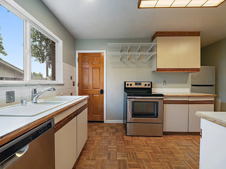 Kitchen with stainless steel appliances. Lots of cabinet and shelf over oven storage. Southern light window over sink and back of unit secondary entrance access door.