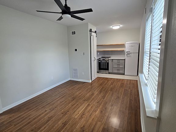 Main living area with ceiling fan and two windows, cable