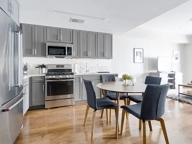 Refined kitchen with grey Shaker cabinets, solid surface backsplash and countertop, high-end Blomberg appliances