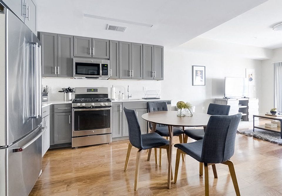 Refined kitchen with grey Shaker cabinets, solid surface backsplash and countertop, high-end Blomberg appliances