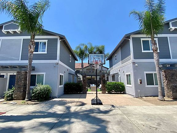 Community area with backetball hoop and sitting area in background at The Nines Townhomes in Escondido, California.