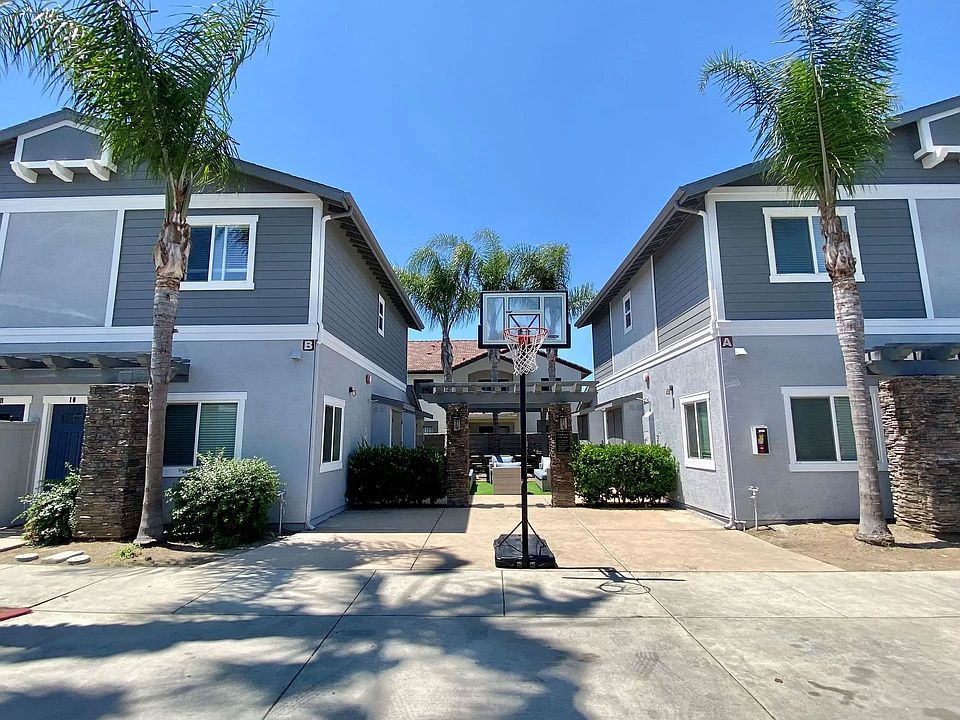 Community area with backetball hoop and sitting area in background at The Nines Townhomes in Escondido, California.