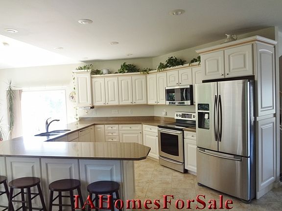 Spacious kitchen with crown molding/maple braid trim cabinets, 16 x 16 tile flooring and eat-in stone countertops overlooking large picture windows of sun room. 