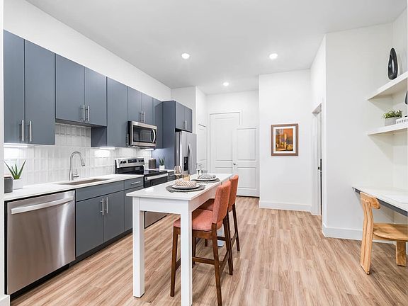 Savor the details at Modera Garden Oaks. Enjoy a modern kitchen with a chrome Symmons pull-down spray faucet and a chic tile backsplash that adds a touch of elegance to your everyday cooking.