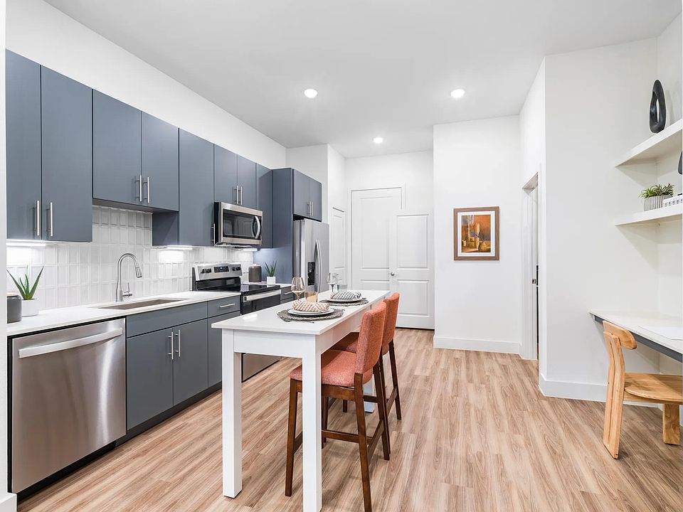 Savor the details at Modera Garden Oaks. Enjoy a modern kitchen with a chrome Symmons pull-down spray faucet and a chic tile backsplash that adds a touch of elegance to your everyday cooking.