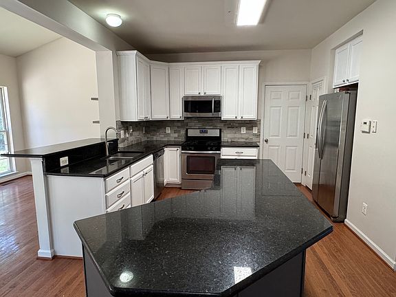 Granite countertops, large island, bar seating, stone tile backsplash, and stainless steel appliances.