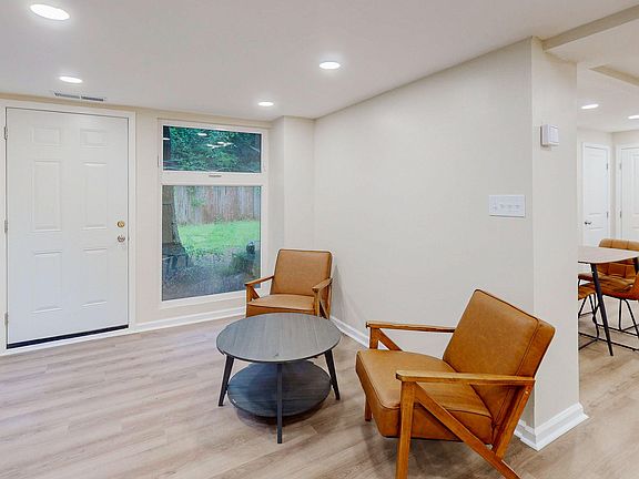 Open living area with recessed lighting, durable flooring, and a seating nook by a large window near the entry.