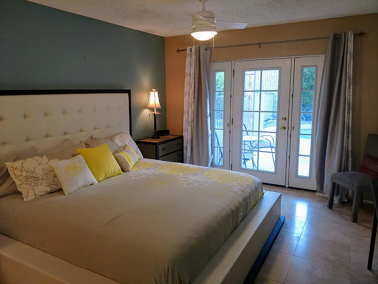 Master suite with king bed and French doors to covered pool patio