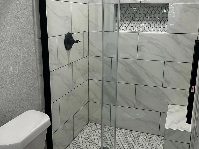 Master bath shower with a sliding glass door.
