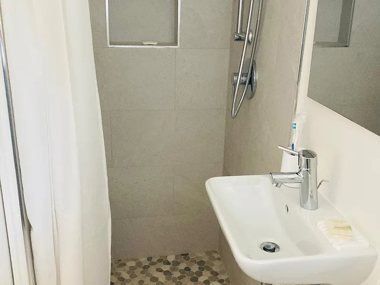 the bathroom, separated by a sliding door, with shower, sink and medicine cabinet