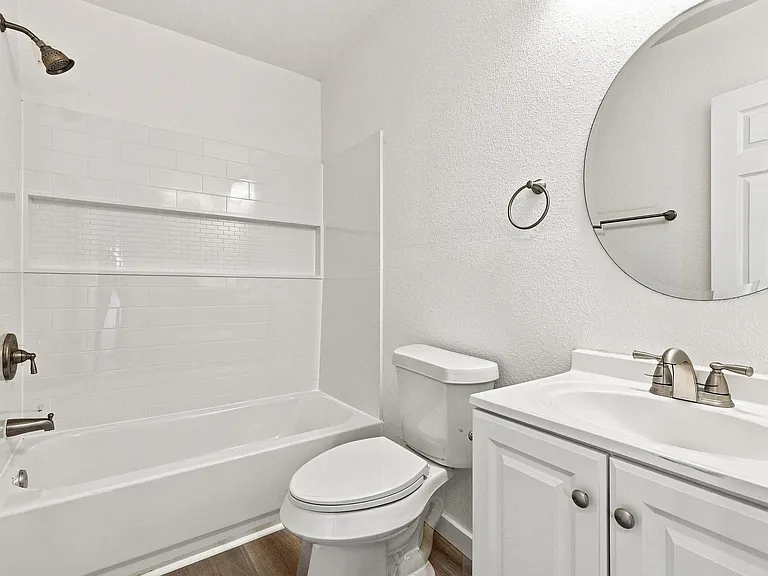 Bathroom featuring a white subway tile shower surround with a mosaic accent band, a soaking tub, a white vanity with a single basin sink, and wood-finish flooring