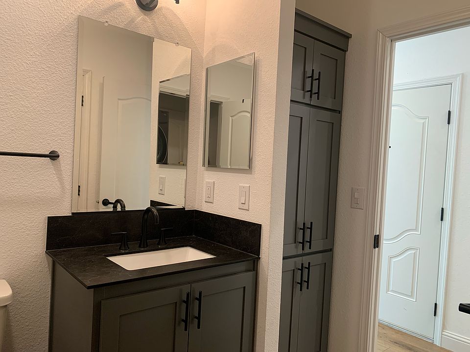 Two mirrors with medicine shelves above the larch sink. Toilet and shower left of the sink. Floor to ceiling cabinet between the sink and the door to the hallway.