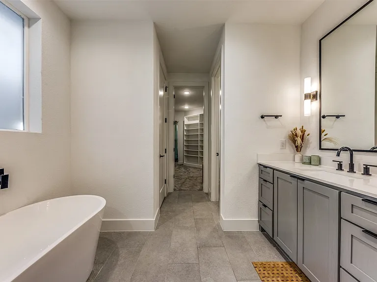 Contemporary bathroom featuring a freestanding tub, a vanity with gray cabinetry and matte black hardware, and a large framed mirror
