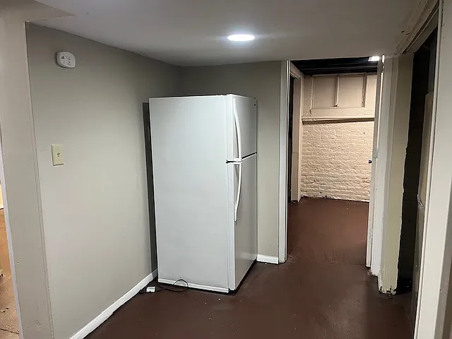 Fridge sits in the common area. This room on the right is the smaller of the 2 bedrooms.