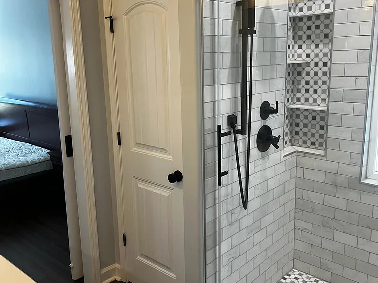 Custom primary shower featuring multiple showerheads, handheld wand, built-in niche, and frameless glass enclosure.