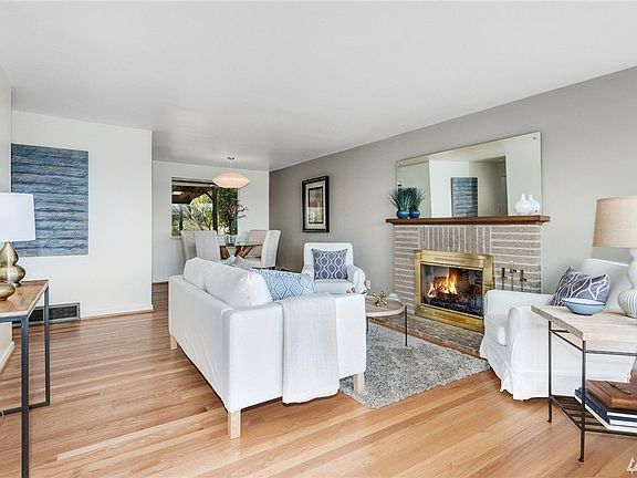Living room with gorgeous oak hardwood flooring and brick wood burning fireplace with custom glass tiled hearth.