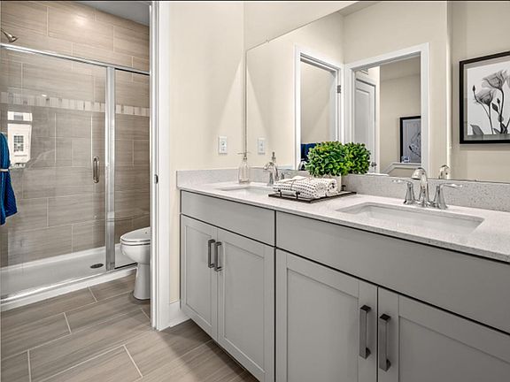 The en-suite bathroom features dual quartz sinks with a full wall-width mirror to promote shared living