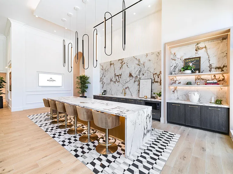 Community demonstration kitchen with a marble island, bar seating, and curated finishes designed for hosting, shared meals, and social gatherings.