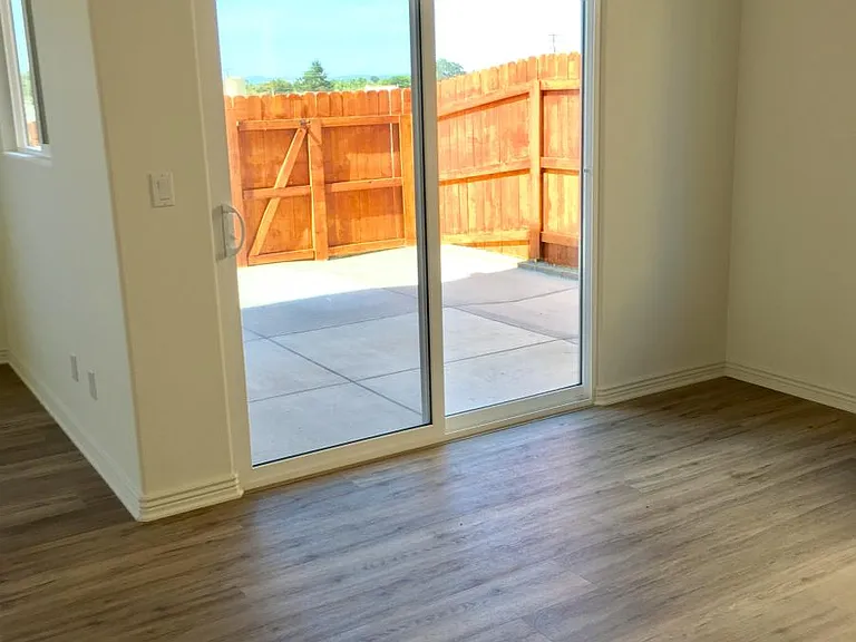 Dining area has a chandelier, with a glass sliding door that opens to a concrete patio.