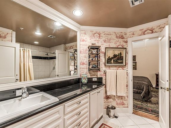 Entering Bathroom from Hallway looking through far door into Bedroom. A great floor plan that allows Bath entry from either. Bathroom features lots of custom built cabinetry with door and drawer storage, slab granite tops, separate toilet closet, and