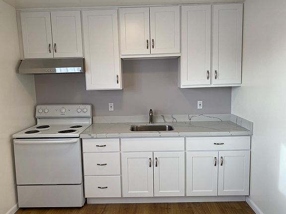 Newly installed hood, self closing cabinets, quartz counter and wood floors