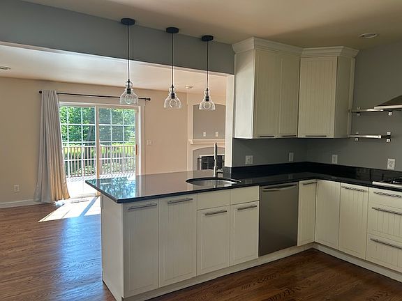 Kitchen with black granite counters open to living/family room and sliding doors to back deck.