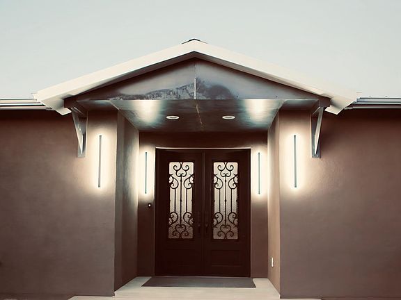 Front of house with metal accented portal and modern lighting.