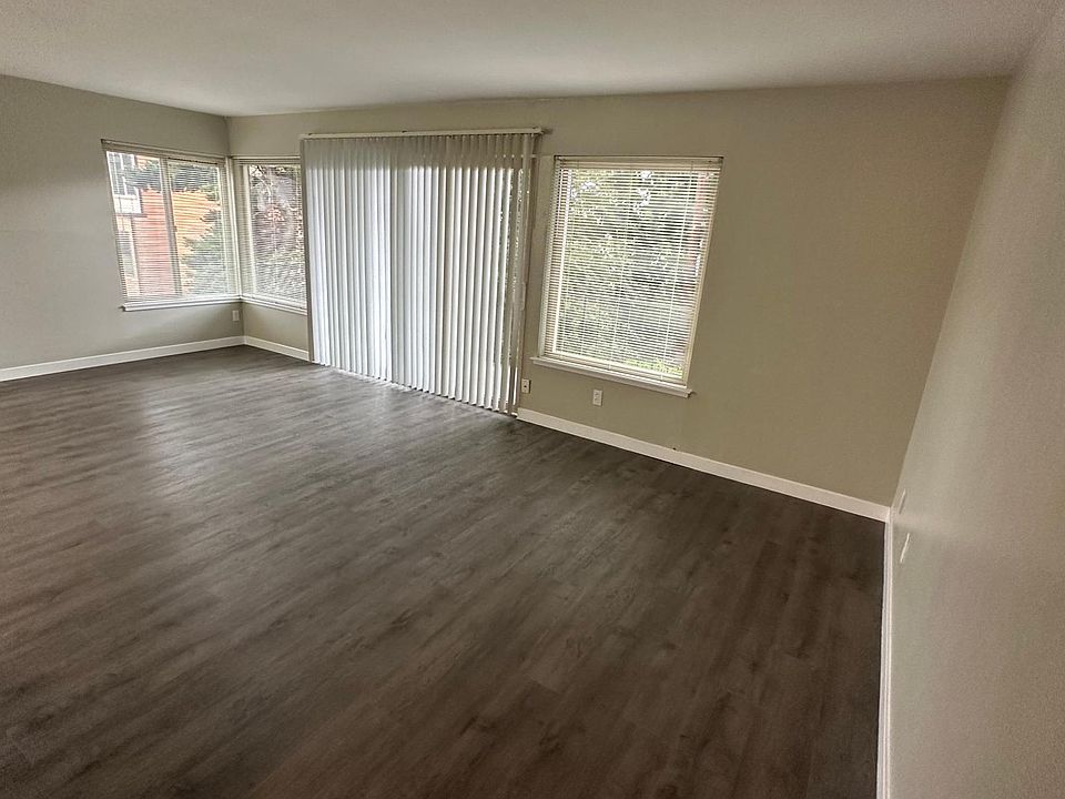 Large living room with balcony and dining room area. West facing balcony and windows and south facing windows in the living and dining area.